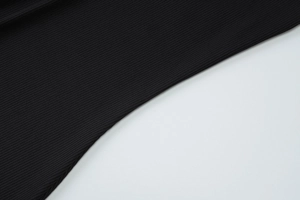 Close-up of black ribbed fabric texture with vertical knitted lines and premium soft finish