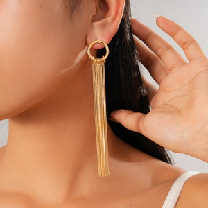 Detailed view of long gold tassel drop earrings with circular studs worn by a model
