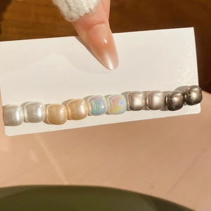 Detail view of a vintage hairpin featuring ten mixed metallic square beads on white card