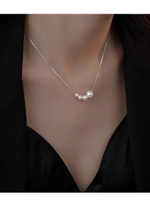 Close-up of four gradient pearls on a silver chain worn with a professional black blazer
