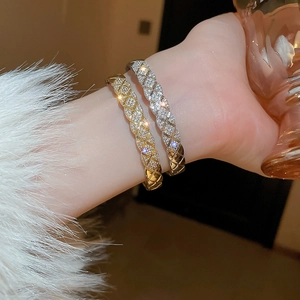 Close-up of gold and silver quilted bangle bracelets with zircon accents on a wrist