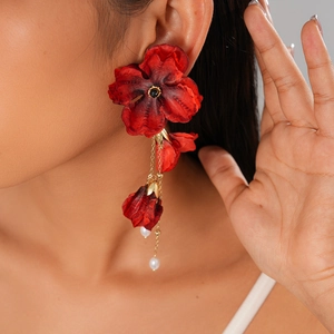 Nahaufnahme eines Models mit roten Stoffblumen-Ohrringen und weißen Imitationsperlen