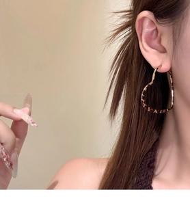 Close-up of model wearing large leopard print heart-shaped hoop earrings with retro resin finish