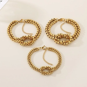 Detail view of three layered gold-plated stainless steel knot bracelets with lobster clasps