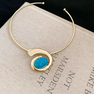Detail of a vintage gold choker necklace featuring a large oval turquoise swirl pendant