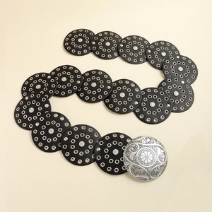 Dettaglio cintura vintage in pelle nera con occhielli metallici e fibbia incisa argento