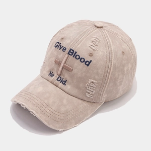 Close-up of distressed khaki baseball cap with Give Blood embroidery and washed cotton texture
