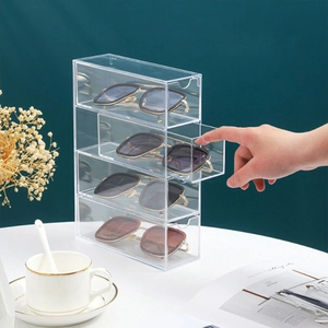 Four-tier clear acrylic drawer organizer for glasses on a desk with elegant home decor