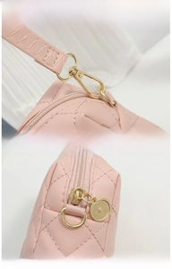 Detail of pink quilted small bag featuring gold rotating metal clasp and durable zipper