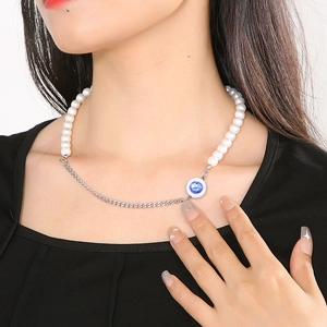 Detail of mixed-style necklace with white pearls, silver chain, and blue gemstone pendant