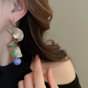 Detail von spiralförmigen Metallohrringen mit grünen und lila Perlen am Model