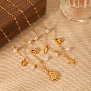 Close-up of golden ocean-themed necklace with starfish, conch pendants and pearls