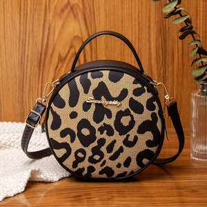 Chic leopard print round crossbody bag with metal handle on a stylish wooden background