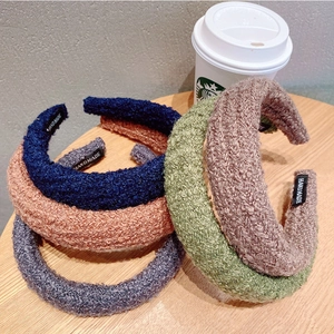 Detailed texture of colorful knit headbands with handmade fabric label on wooden surface
