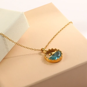 Detailaufnahme von Delfin-Anhänger mit meeresblauem Edelstein und geriffeltem Goldrand