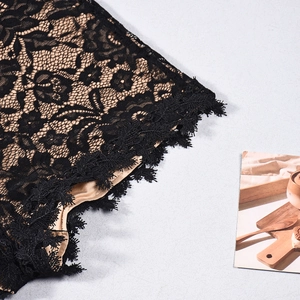 Detailed macro view of black floral lace fabric with fringe trim and beige lining