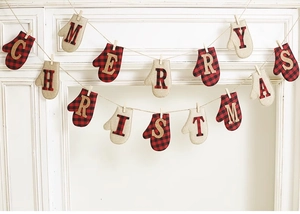 Close-up of flannel and linen Merry Christmas glove banners hanging on a white fireplace