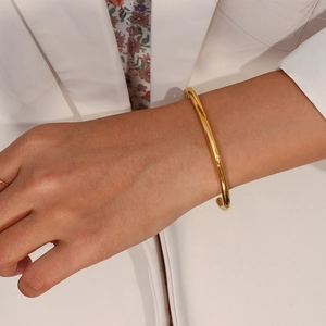 Minimalist 18K gold plated stainless steel open bangle worn with an elegant outfit