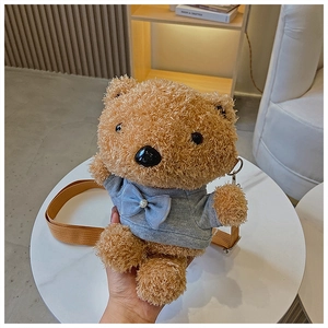 Close-up of a brown teddy bear plush bag with a gray T-shirt and blue bow accessory