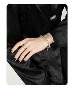 Close-up of S925 sterling silver OT-buckle bracelet and two-tone ring on black blazer