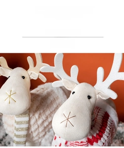 Close-up of plush Christmas reindeer ornaments with knit sweaters and striped scarves