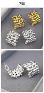 Close-up of woven texture design on C-shaped gold and silver hoop earrings