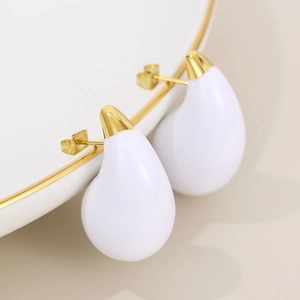 Detailed view of teardrop earrings with gold-plated hammering and white enamel finish