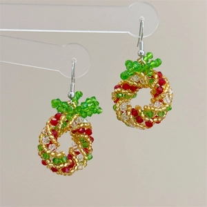 Macro detail of handmade beaded Christmas wreath earrings with crystals and red bows