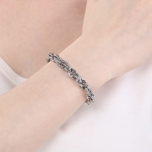 Détail d'un bracelet gourmette torsadé épais en argent porté sur le poignet d'un mannequin