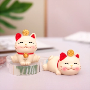 Detail of cute lucky cat figurines with golden coins for home or car dashboard decor