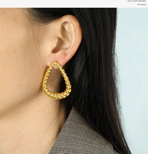 Detail showing high-quality golden twisted drop earring on a model in luxury style