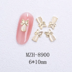 Detailed view of 6x10mm gold butterfly nail charms with white opal stones and pink nail art