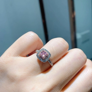 Close-up of pink square zircon ring with halo diamonds on a woman's hand