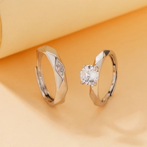 Detail of silver couple rings set with round-cut crystal and geometric facets
