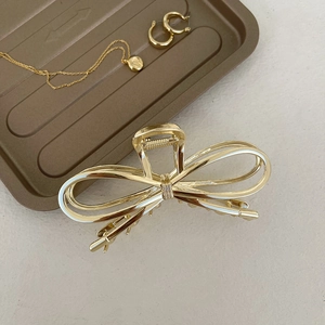 Macro detail of the golden double-line hollow bow hair claw clip in a luxury setting