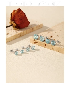 Detailed view of four pairs of round light blue zircon studs on silver metal setting