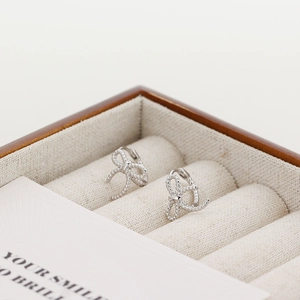 Detail of S925 silver bow earrings with twisted rope texture in a velvet jewelry box