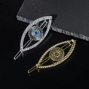 Detail of silver rhinestone and golden evil eye hair clips on a dark stone surface