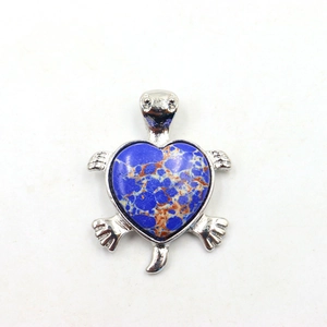 Detail van een zilveren schildpashanger met een hartvormige blauwe edelsteen inlegwerk