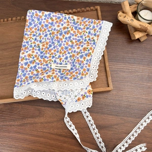 Close-up of floral cotton headscarf with white lace trim and 100% cotton label