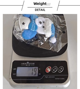 Christmas blue plush bear ornament with silver star bell shown on a digital scale