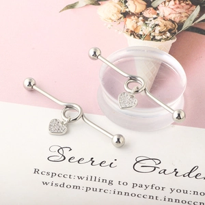 Detailed macro view of silver cross heart industrial barbell studs with clear zircon stones
