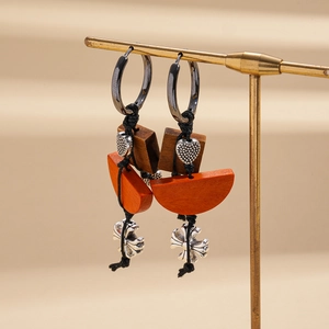 Detailed shot of ethnic earrings with wooden blocks and silver cross pendants