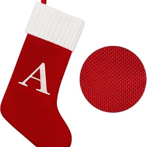 Macro view of red knitted Christmas stocking with white embroidered letter A detail