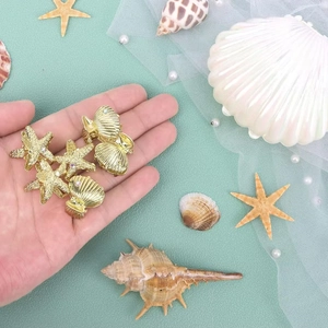 Golden starfish and seashell hair clips held in hand with ocean-themed props