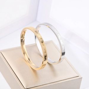 Macro detail of gold and silver steel bangles with etched tiny footprint patterns