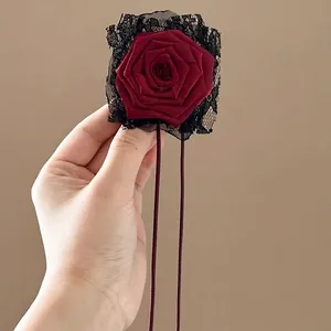 Detail of dark red fabric rose hair tie with black lace trim and long ribbon ties
