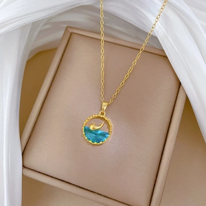 Elegant gold titanium whale necklace with blue crystal pendant on silk fabric background