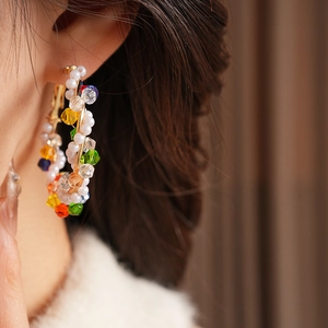 Close-up of vintage round earrings with multicolored beads and pearls on model