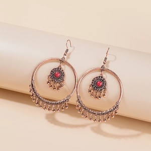Macro shot of bohemian bronze hoop earrings with turquoise stone and metal fringe tassels